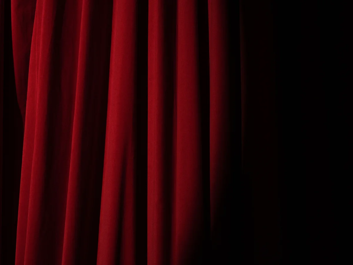 A red velvet theatre curtain lit by a spotlight
